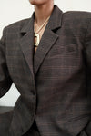 Close-up detail of brown windowpane plaid Archer Blazer showing notched lapel and textured fabric, styled with gold chain necklace