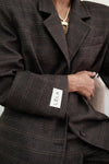 Close-up detail of brown windowpane plaid Archer Blazer showing white LÉLA branded label patch on cuff