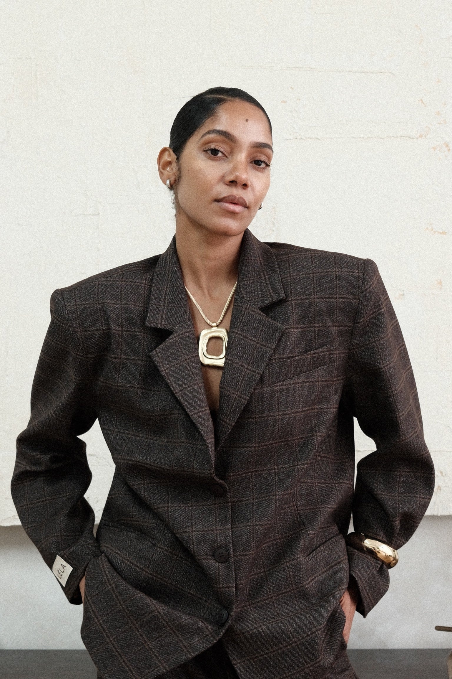 Model wearing brown windowpane plaid Archer Blazer with matching pants, paired with gold necklace in front of white background