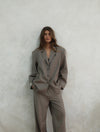Front view of model wearing beige Carter Blazer with matching pants, hands in pockets, showing relaxed oversized fit against white background