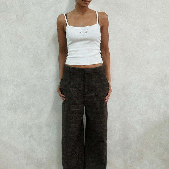 Front view of model wearing brown windowpane plaid Carter Pants with white LÉLA tank top, showing high-waisted wide-leg fit against white background