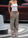 Model wearing beige Carter Pants with white LÉLA tank top in urban street setting with red car in background