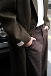 Detail shot of dark green Beaumont Coat showing double-breasted buttons and LÉLA branded label, styled with white t-shirt and brown LÉLA Archer pants next to silver Land Rover Defender