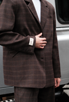 Close-up of brown windowpane plaid Archer Blazer styled with matching pants in front of silver car