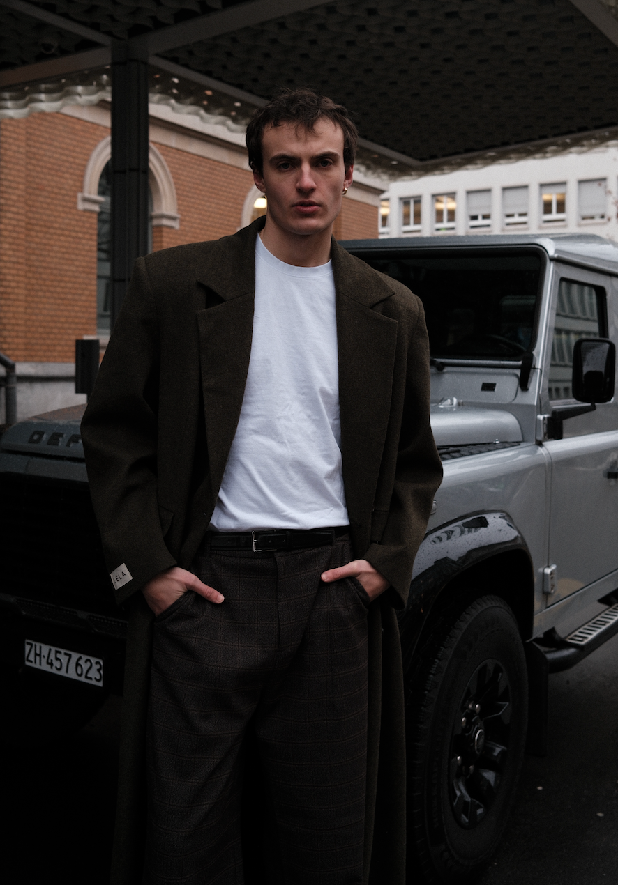 Close-up detail of brown plaid Carter pants showing windowpane check pattern and LÉLA Beaumont Coat , styled with white t-shirt